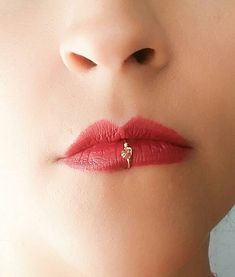 a woman's lips with a gold ring on top of her lip and nose