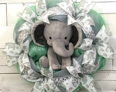 an elephant wreath with silver and green ribbons on a white wooden background is the perfect addition to any baby's room