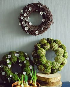 two wreaths are sitting next to each other on a table with flowers and plants