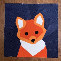 an orange and white paper cut out of a fox on a wooden table with blue polka dots