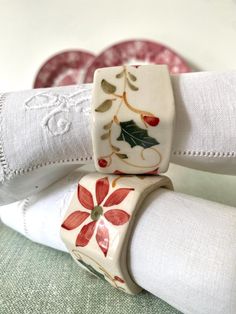 two napkins are sitting on top of each other, decorated with holly leaves and red berries