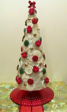 a white christmas tree with red and green buttons on it's top sitting on a table