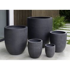 four black vases sitting next to each other in front of a door and steps