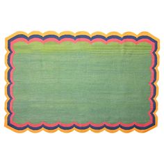 a green rug with pink and yellow trimmings on the edges, against a white background