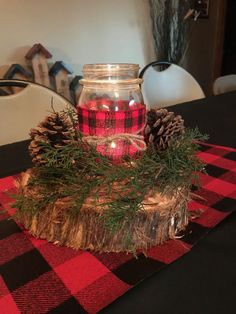 a glass jar filled with red and black candles sitting on top of a table