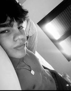 a young man laying in bed with his head on the pillow looking at the camera