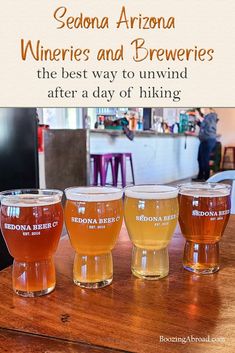 four glasses filled with beer sitting on top of a wooden table