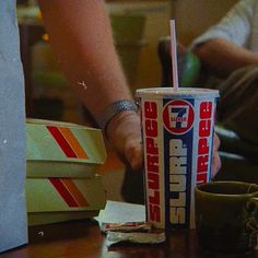 a person holding a drink in their hand next to some boxes and papers on the table