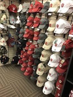 many hats are hanging up on the wall in a store, and there is no image here to provide a caption for