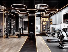 a gym with rows of exercise equipment in the center and lots of lights on the ceiling