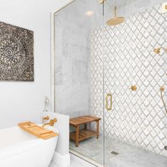 a white bathtub sitting next to a walk in shower under a painting on the wall