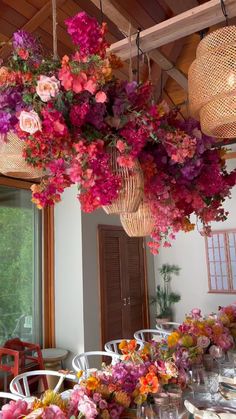 the flowers are hanging from the ceiling above the tables