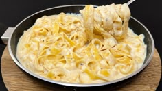 a skillet filled with macaroni and cheese on top of a wooden cutting board