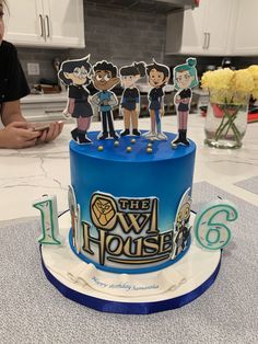 a blue cake with cartoon figures on top and the number six in front of it