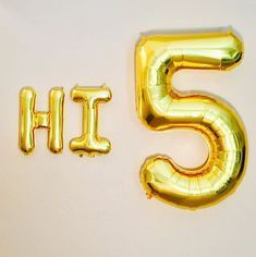 the number five is made out of gold foil balloons and sits on a white surface