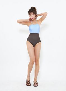 a woman in a blue and black one piece swimsuit with her hands on her head