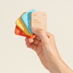 a hand holding four different colored plastic coasters in it's left hand,