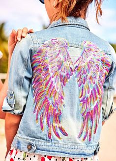 a woman wearing a jean jacket with an angel design on it