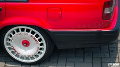 the front end of a red car with white spokes