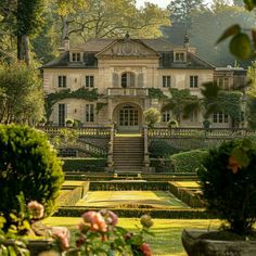 a large house with lots of trees and bushes around it's front entrance, as seen from across the garden