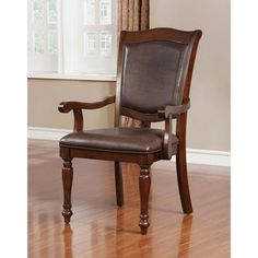 a brown leather chair sitting on top of a hard wood floor next to a window