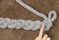 someone is pulling the end of a rope with their fingers on it and pointing at it