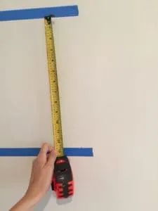 a person holding a measuring tape and a pair of scissors in front of a wall