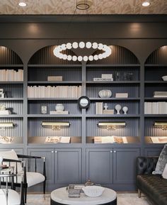 a living room filled with furniture and bookshelves next to a clock on the wall