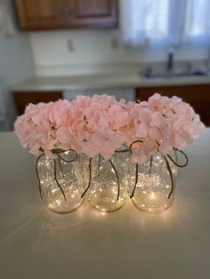 three mason jars filled with pink flowers sitting on top of a table