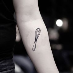 a person with a tattoo on their arm holding a whisk