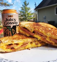 a sandwich cut in half sitting on top of a white plate next to a can of juice