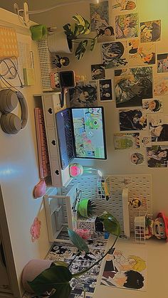 a computer monitor sitting on top of a desk in front of a wall covered with pictures