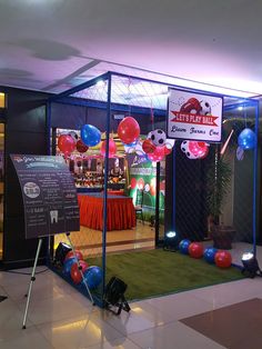 the entrance to an event with balloons and signs on display in front of it's glass enclosure