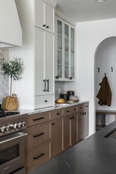 a kitchen with white cabinets and black counter tops, an arched doorway leading into the dining room