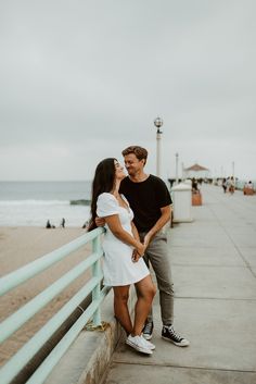 a man and woman standing next to each other near the ocean