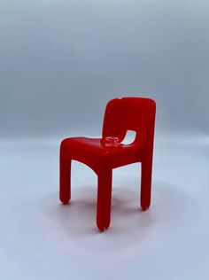 a red plastic chair sitting on top of a white floor next to a cup holder