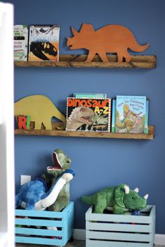 two bookshelves with dinosaurs on them in a child's room, one is blue and the other is green