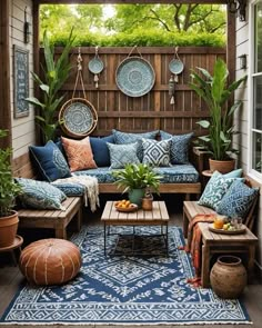 an outdoor living room with blue and white pillows on the couches, potted plants and