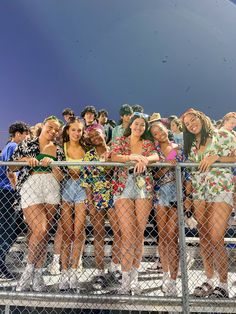 group of young women standing behind a chain link fence