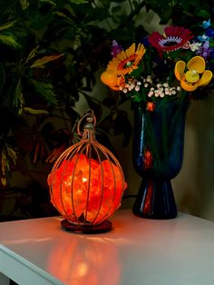 an orange lantern sitting on top of a table next to a vase filled with flowers