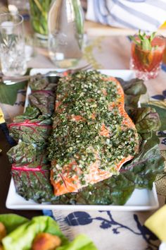 a plate topped with salmon and vegetables on top of a table next to other plates