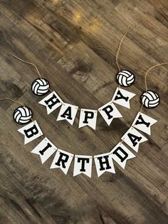 a happy birthday banner with volleyballs and balls hanging from strings on a wooden floor