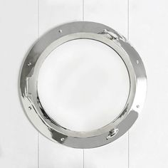 a metal porthole mounted to the side of a white wall