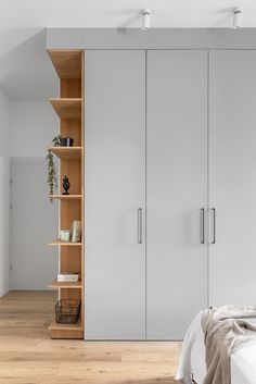 a bedroom with white walls and wooden flooring, built - in shelving units