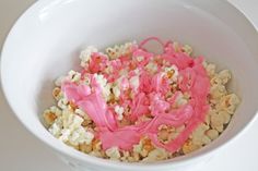 a white bowl filled with popcorn covered in pink icing