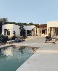 a house with a pool in front of it and some chairs around the pool area