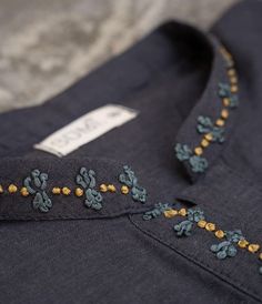 a close up of a blue shirt with embroidered flowers on it