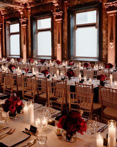 the tables are set with candles and place settings for an elegant wedding reception in front of large windows