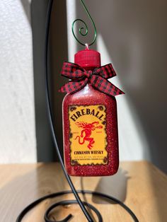 a red bottle with a black ribbon on it sitting on top of a wooden table