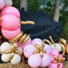 some balloons are tied to the back of a chair with gold bows on them and pink, white, and brown balloons